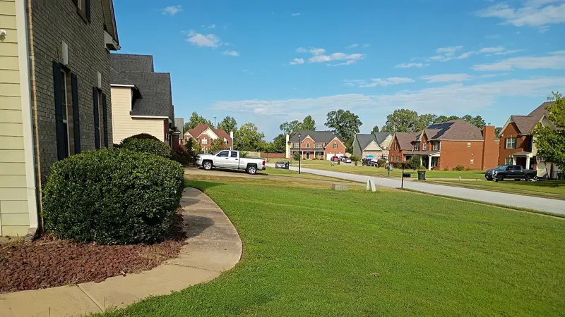 Freshly cut front lawn and rounded shrubs along a brick two-story in a Columbus-area subdivision